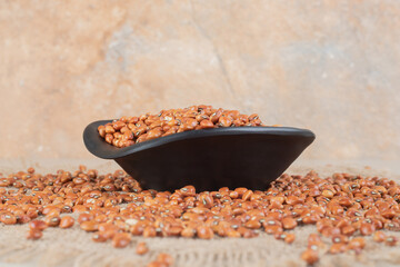 Fototapeta na wymiar Brown beans isolated in a ceramic cup on concrete background