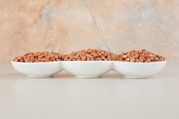 Brown beans isolated in a ceramic cup on concrete background