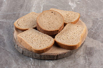 Brown bread slices on a wooden board on marble background