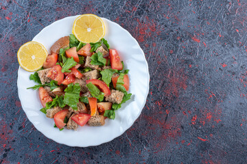  Dried crust mixed into vegetable salad with lemon garnish on dark colored background
