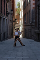 Tango dancing couple. Boy in a suit and shirt, girl in shorts and a t-shirt. dance, street, argentinian