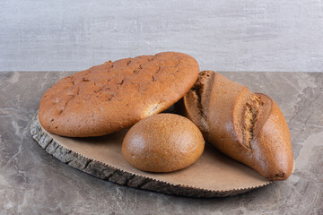 Assortment of bread loaves on a wooden board on marble background