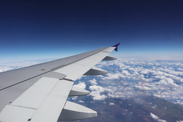 Aerial view from window of aircraft show aircraft wing and engine with horizon deep blue sky above all white clouds for transportation and travel airline business presentation background.