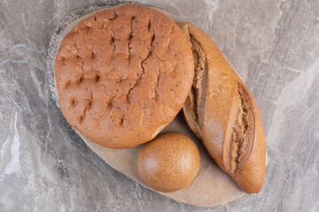 Assortment of bread loaves on a wooden board on marble background