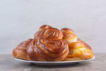 Roll of tablecloth and a basket of sweet buns on marble background