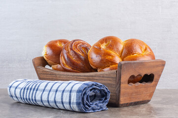 Roll of tablecloth and a basket of sweet buns on marble background