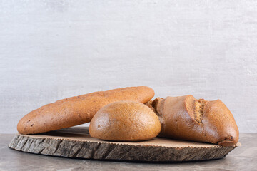Assortment of bread loaves on a wooden board on marble background