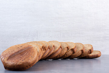 Black bread slices lined up on marble background