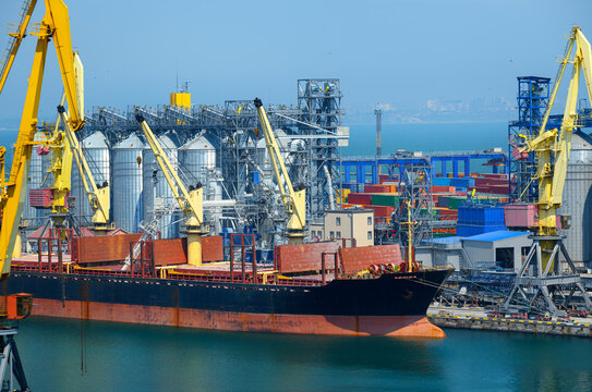industrial seaport infrastructure, sea, cranes and dry cargo ship, grain silo, bulk carrier vessel and grain storage elevators, concept of sea cargo transportation