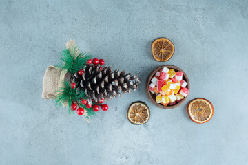 Bowl of candies, dried lemon slices and a christmas decoration on marble background