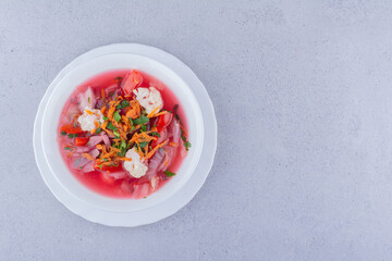 Cabbage soup with carrot and cauliflower topping on marble background