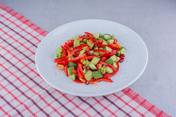 Cucumber, pepper and lettuce salad on a tablecloth on marble background
