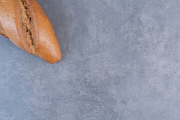 Single loaf of baton bread on marble background