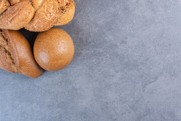 Loaves of baton, strucia and bun bread bundled on marble background