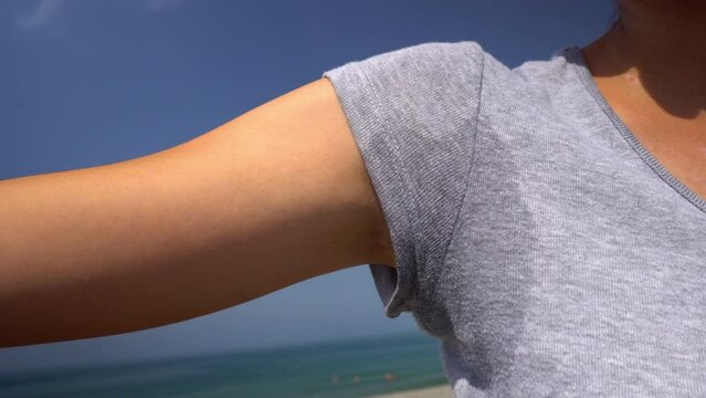 Close-up of woman with hyperhidrosis of sweating. Young with sweat stain on her clothes outside by sea. Healthcare concept. hyperhidrosis sweats under arm, does not feel well with body,