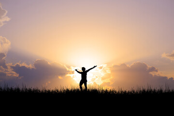 Silhouette of a man standing with his hands up. happily in the meadow
