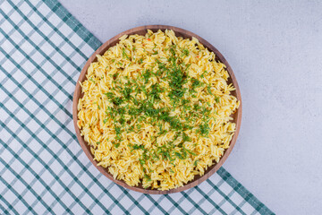 Wooden tray filled with freshly cooked brown rice pilaf on marble background
