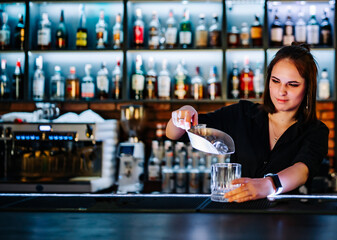 Portrait of young attractive woman bartender Making Cocktail in bar