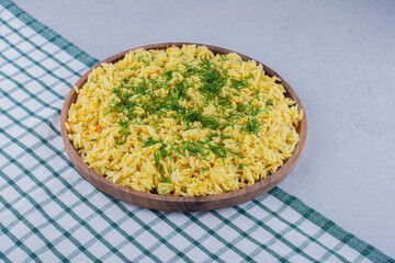 Large pilaf serving garnished with chopped dill on marble background