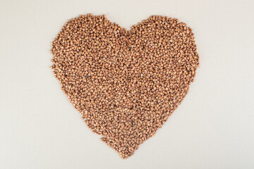 Buckwheat seeds in heart shape on concrete background