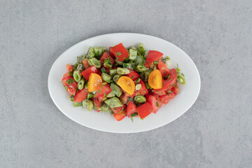 Red cherry tomatoes and green beans salad in a ceramic dish