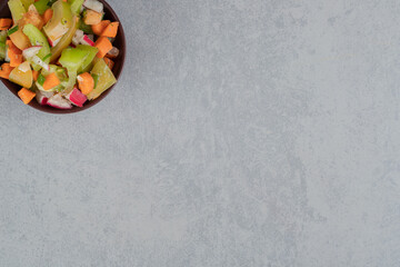 Fruit salad in a wooden cup on a concrete background