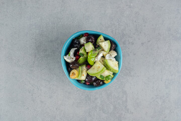Fruit salad in a blue cup with black olives