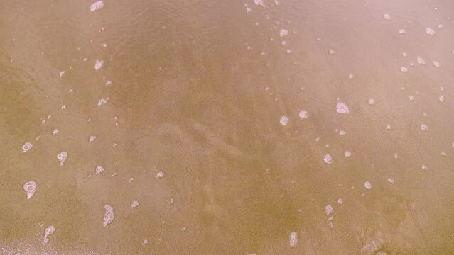 Figures 2024 on golden sand of beach. New Year's Eve concept. Top view of rooms painted on sand of coastline with foamy waves. Wave of water washes away inscription. Christmas and New Year concept.