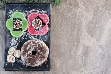 Obraz na płótnie Canvas Glazed donut, turkish delights and marmelades on a platter on marble background