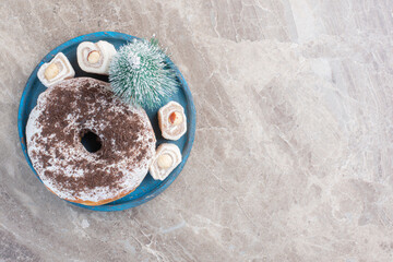 Blue platter with turkish delights, tree figurine and a donut on marble background