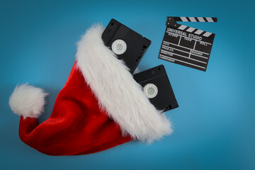 Two retro videotapes in a santa claus hat and a movie clapperboard on a blue .