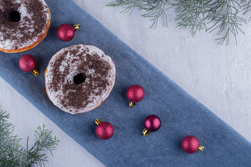 Composition of delicious donuts and christmas decorations on a folded tablecloth on white background