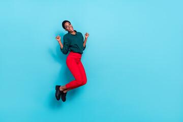 Fototapeta na wymiar Photo of funny lucky trans person dressed green shirt jumping high rising fists empty space isolated blue color background