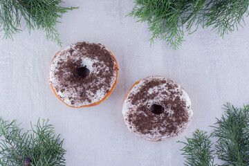 Arrangement of donuts amid cypress leaves on white background