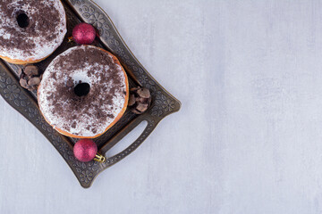 Pairs of cypress cones, donuts and christmas decorations on a platter on white background