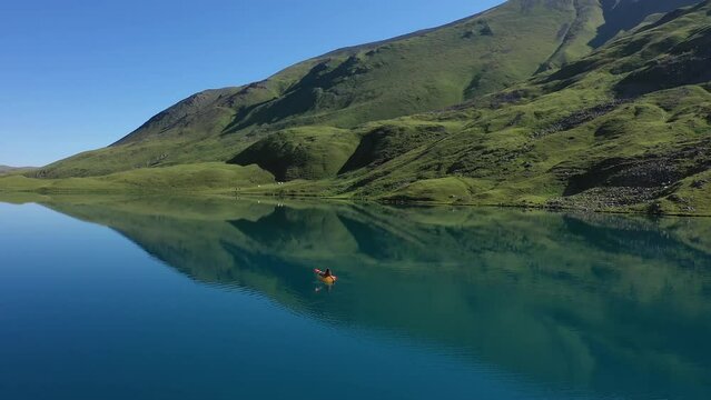 Panoramic View Of Mountain Lake with Woman Paddling on Packraft