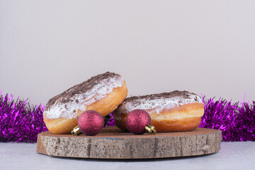 Glazed donuts on a wooden board and purple garland on white background
