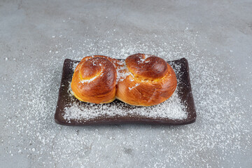 Coconut powder covered platter with sweet buns on marble background