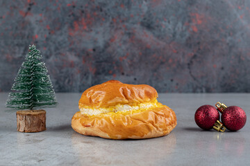 Christmas tree figurine, sweet gun and decorative balls arranged on marble background