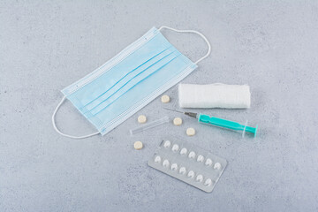 Mask, ampoule, syringe and medical pills on marble background