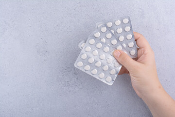 Woman hand holding three packs of pills on marble background