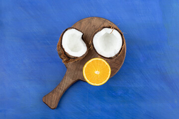 A wooden cutting board with sliced coconut and orange