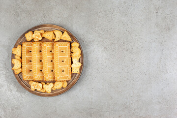 A wooden board full of biscuits on marble background