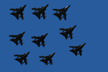 Silhouettes of nine military aircraft in flight bottom view against the blue sky