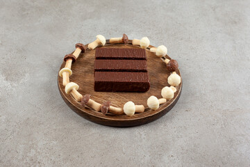 A wooden plate with chocolates and wooden bowl with sweet mushrooms