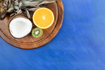 A wooden board with sliced fruits on blue background