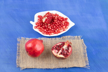 A white plate full of pomegranate on blue background