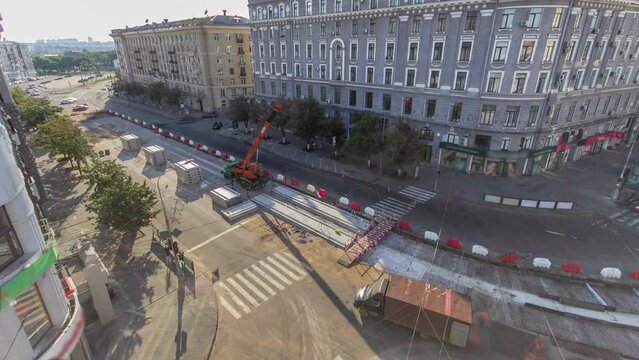 Installing concrete plates by crane at road construction site timelapse. Industrial workers with hardhats and uniform. Aerial panoramic top view. Reconstruction of tram tracks in the city street