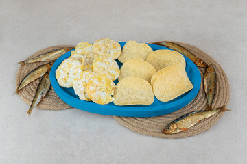 Crispy snacks on blue plate with dry fish