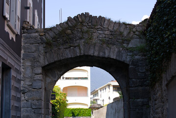 Stone gate at alley at village Ascona, Canton Ticino, on a sunny summer day. Photo taken July 24th, 2022, Ascona, Switzerland.